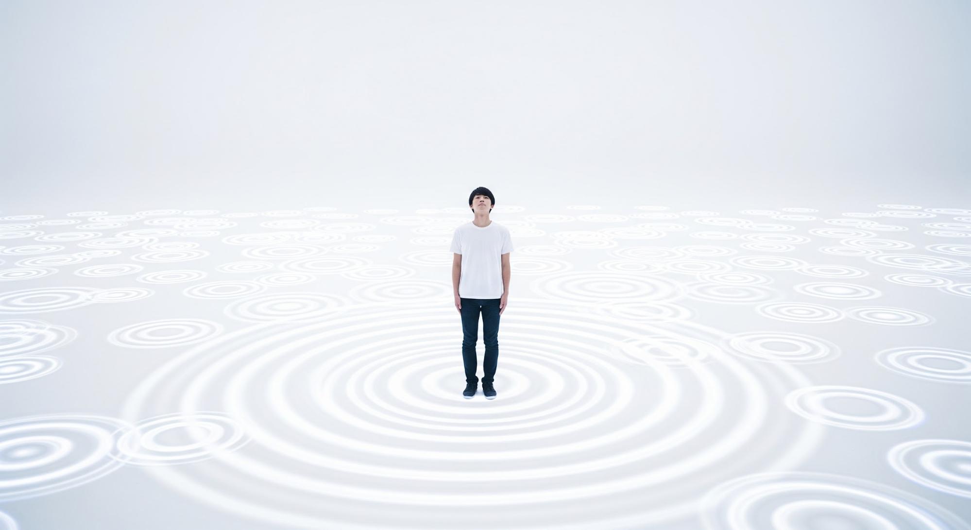 男性が、真っ白な空間の中に立っている。彼を中心に無数の波紋が広がっている。